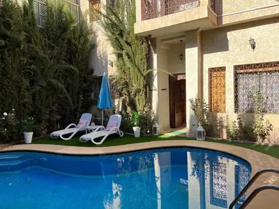 a swimming pool with two lawn chairs and an umbrella at Villa in Marrakesh Targa with swimmingpool in Marrakech