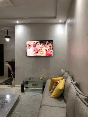 a living room with a couch and a tv on a wall at Appartement hay mabroka in Marrakech