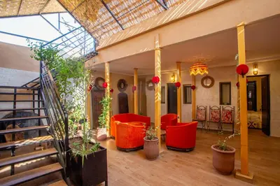 a lobby with red chairs and plants and a staircase at Auberge Prince in Marrakech