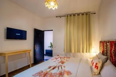 a bedroom with a white bed and a tv at Auberge Prince in Marrakech
