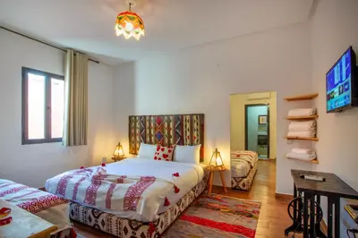 a bedroom with two beds and a tv at Auberge Prince in Marrakech