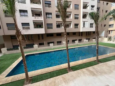 a swimming pool in front of a building with palm trees at Duplex Menara Garden 2 in Marrakech