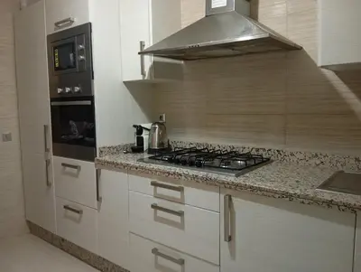 a kitchen with white cabinets and a stove top oven at Appartement prestigia golf in Marrakech