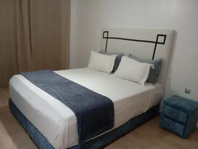a bedroom with a large bed with a blue stool at Appartement prestigia golf in Marrakech
