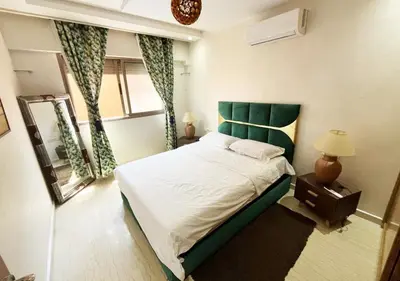 a bedroom with a bed with a green headboard and a mirror at duplex prestige Gueliz in Marrakech
