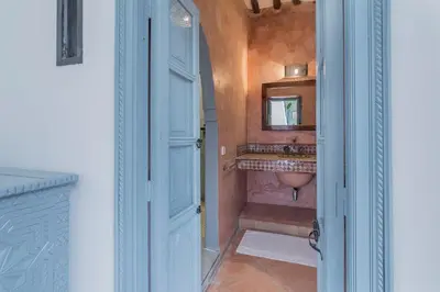 a bathroom with a sink and a mirror and a door at Riad HØBÖ-CHIC privé Medina rooftop WI-FI Fibre in Marrakech