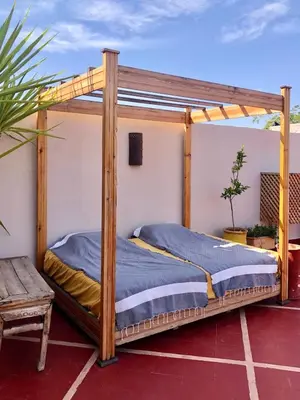 a wooden bed with a canopy on a patio at Riad HØBÖ-CHIC privé Medina rooftop WI-FI Fibre in Marrakech