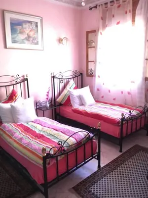 two beds in a bedroom with pink walls at Appartement Andalou in Marrakech