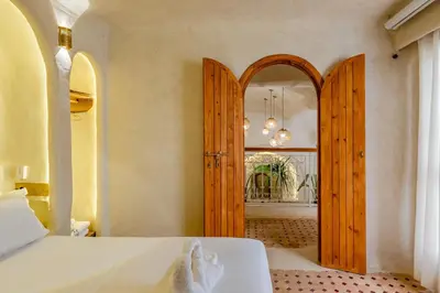 a room with two wooden doors and a room with a table at DarNiama - 3 Suites & Private Pool - Gueliz Center in Marrakech