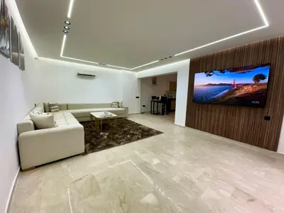 a living room with a couch and a tv on a wall at Chic duplex luxury3suites et wi-fi in Marrakech