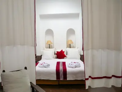 a bedroom with a large white bed with red pillows at Riad Dar Aman in Marrakech