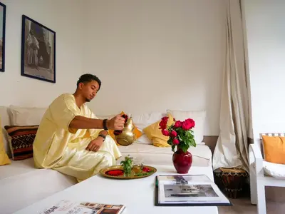 a man is sitting on a couch with a table at Riad Dar Aman in Marrakech