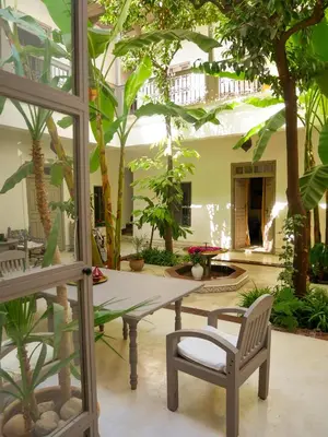 a patio with a table and chairs and trees at Riad Dar Aman in Marrakech