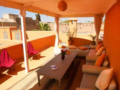a balcony with couches and tables on a roof at Riad Dar Aman in Marrakech