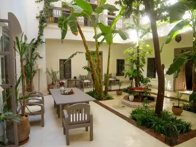 a courtyard with a table and chairs and trees at Riad Dar Aman in Marrakech