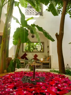 a table with red rose petals on the ground at Riad Dar Aman in Marrakech
