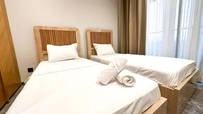 two beds with white sheets and a towel on them at Cocon Stylé & Spacieux au Cœur de Ville in Marrakech