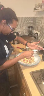 a woman making a pizza in a kitchen at atelier de cuisine in Marrakech