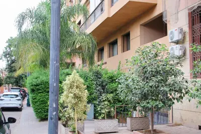 a building with a bunch of trees next to a street at Gueliz Appartement in Marrakech