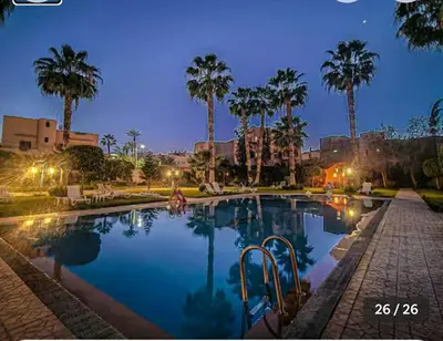 a swimming pool with palm trees in a park at Appartement Marrakech in Marrakech