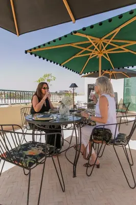 two women sitting at a table under an umbrella at Riad Palazzo Montefiore in Marrakech