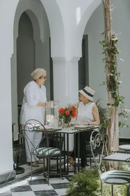 two women sitting at a table on a patio at Riad Palazzo Montefiore in Marrakech