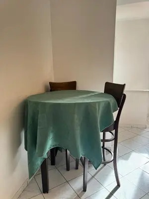 a table with two chairs with a green table cloth on it at Al Qaria Syahia Duplex Moufid in Marrakech