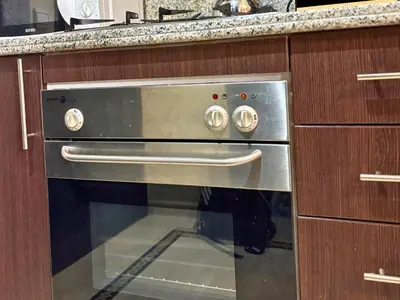 a stainless steel oven in a kitchen with wooden cabinets at Trésor de Gueliz avec Piscine et Terrasse in Marrakech