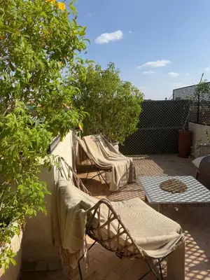 a patio with two chairs and a table and trees at Riad Secret by Dar n alla in Marrakech