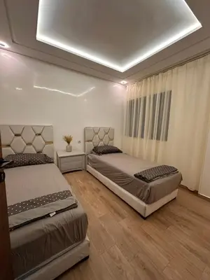 a bedroom with two beds and a window with curtains at appartement luxueux au centre vlle avec piscine in Marrakech