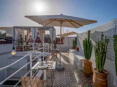 a patio with a table and umbrella on a roof at Riad Fleur De Sable in Marrakech