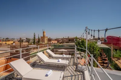 a balcony with lounge chairs and a view of a city at Riad Fleur De Sable in Marrakech
