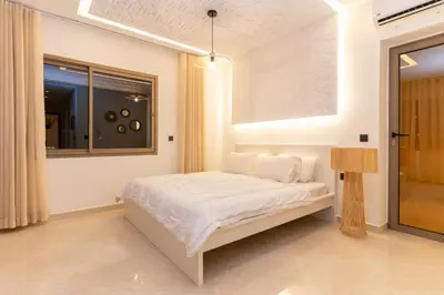 a white bedroom with a bed and a window at Villa Meraki in Marrakech