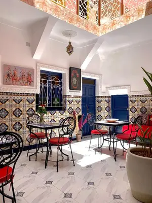 a restaurant with tables and chairs in a room with tiles at Riad Zifamo in Marrakech