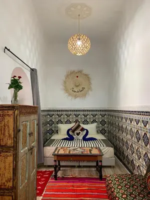 a bedroom with a bed and a table and a chandelier at Riad Zifamo in Marrakech
