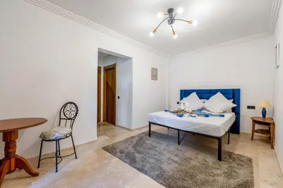 a bedroom with a bed and a table and a chair at Marrakech Duplex Haut Standing, Piscine et Jardin Privé in Marrakech