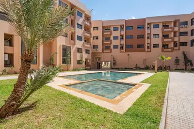 an apartment building with a swimming pool and a palm tree at Marrakech Duplex Haut Standing, Piscine et Jardin Privé in Marrakech