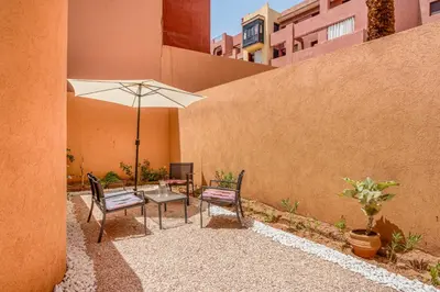 a patio with a table and chairs and an umbrella at Marrakech Duplex Haut Standing, Piscine et Jardin Privé in Marrakech