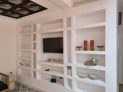 a living room with white shelves and a tv at Riad MAGE Marrakech in Marrakech