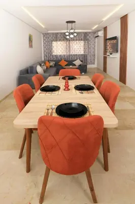 a dining room table with orange chairs and a couch at 2 Bedroom flat - Marrakech in Marrakech