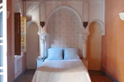 a bedroom with a bed with an arched window at Riad Bleu-Azrak in Marrakech