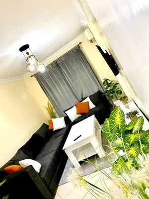 a living room with a black couch and some plants at Bright Modern Apartment Marrakech City Center, Walk Everywhere in Marrakech