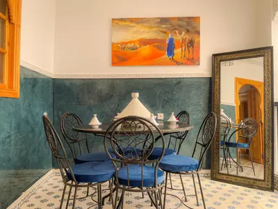 a dining room with a table and chairs and a painting at Antaki retreat Marrakech in Marrakech