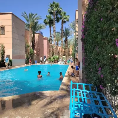 a group of people in a swimming pool at a resort at maison Noé , chambre au rez de chaussée ,un lit double, sale de bain privative séparer in Marrakech