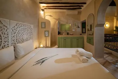 a bedroom with a large bed and a kitchen at Riad Privé Dar El Khamsa-Petit Dej inclus in Marrakech