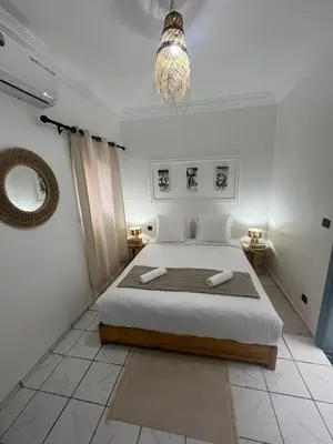 a white bedroom with a bed and a chandelier at RIAD Al QARYA 4 chambres in Marrakech