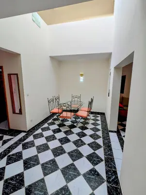 a room with a table and chairs on a checkered floor at Duplex Marakech Dotea Lilia in Marrakech