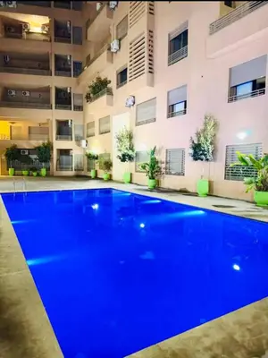 a swimming pool in front of a building with blue lighting at Appart Duplex 3ch Piscine in Marrakech