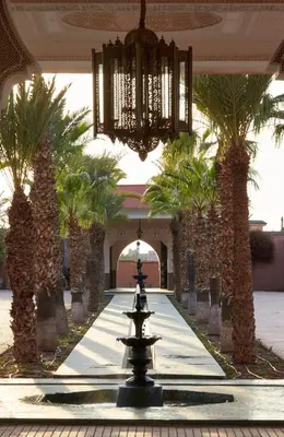 a fountain in a lobby with palm trees and a chandelier at L Mansion Villa in Najem