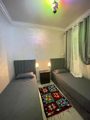 two beds sitting in a room with a window at lUXEE APPARTEMENTN BELLE in Marrakech